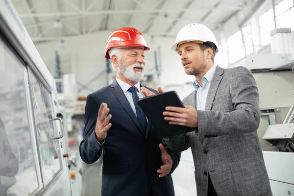 İş arkadaşları fabrikada iş konuşuyor. Projede çalışan mimarlar.