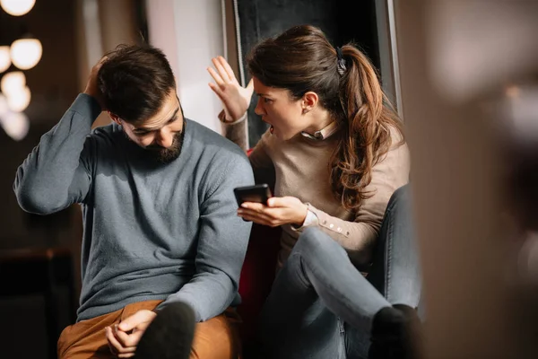 Angry couple or marriage fighting for a mobile phone at home. Jealous woman holding smartphone and showing message to his husband