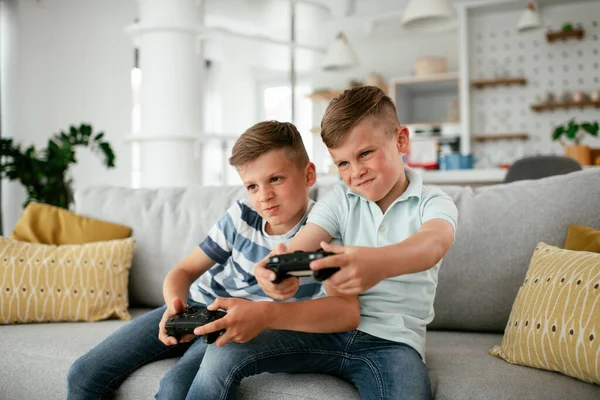 Video oyunu oynayan mutlu kardeşler. Küçük kardeşler oturma odasında video oyunu oynarken eğleniyorlar.