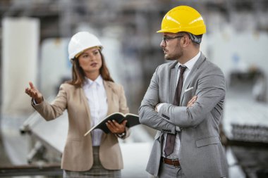 Erkek ve kadın iş tartışıyorlar. Fabrikada çalışan meslektaşlar.