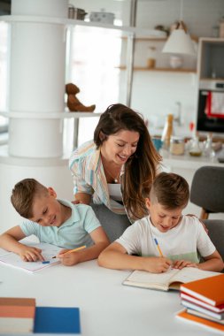 Anne oğullarıyla ödev yapıyor.