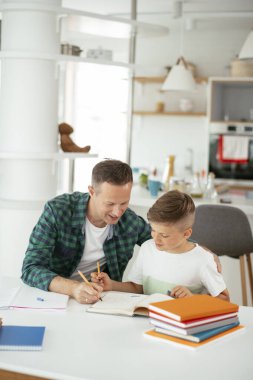 Baba, oğluna ev ödevinde yardım ediyor. Küçük çocuk evde öğreniyor..