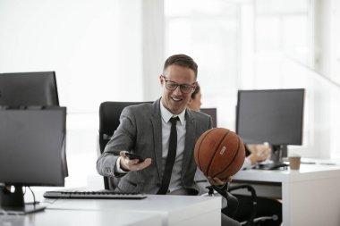 Ofiste basketbolla oynayan yakışıklı bir iş adamı. Genç işadamı çalışırken eğleniyor.