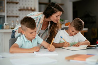 Anne oğullarıyla ödev yapıyor.