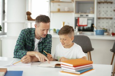 Baba, oğluna ev ödevinde yardım ediyor. Küçük çocuk evde öğreniyor..
