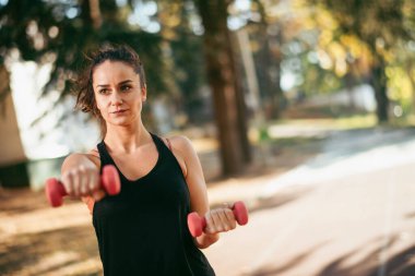 Genç bir kadın dışarıda egzersiz yapıyor. 