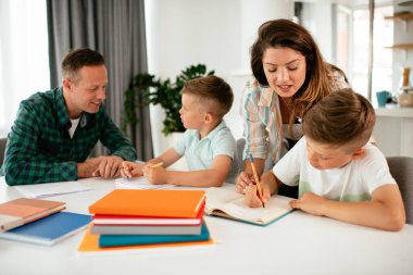 Ebeveynler çocuklara ev ödevlerinde yardım ediyorlar. Küçük çocuklar evde öğreniyor..