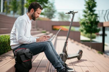 Genç iş adamı dışarıda. Laptop kullanan yakışıklı iş adamı