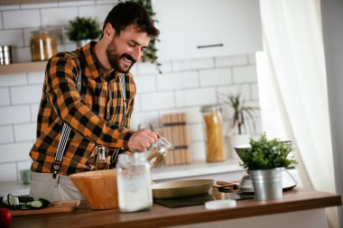 Mutfaktaki yakışıklı adamın portresi. Genç adam lezzetli yemekler hazırlıyor..