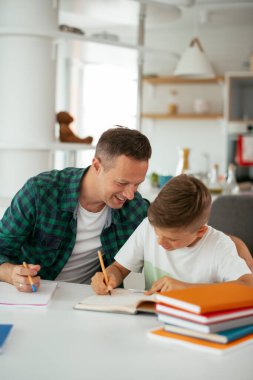 Baba, oğluna ev ödevinde yardım ediyor. Küçük çocuk evde öğreniyor..