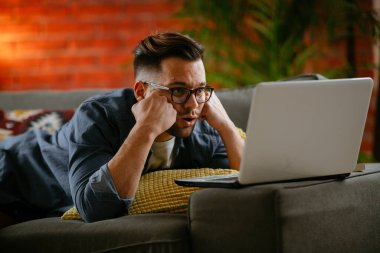 Evdeki dizüstü bilgisayarda dizi izleyen bir adam..