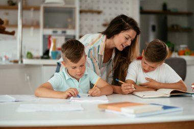 Anne oğullarıyla ödev yapıyor.