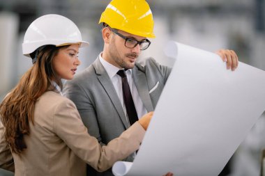 Fabrikadaki iş adamı ve iş kadını. Fabrika üretim hattında kalite kontrolde çalışan iki profesyonel insan..