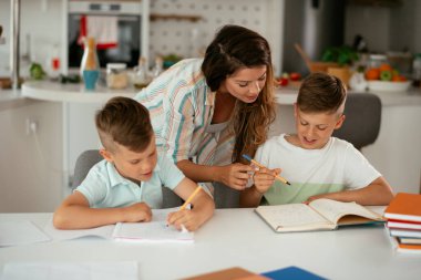 Anne oğullarıyla ödev yapıyor.
