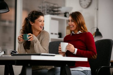 Açık uzay ofisinde konuşan ve gülen mutlu iş kadınları