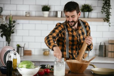 Mutfaktaki yakışıklı adamın portresi. Genç adam lezzetli yemekler hazırlıyor..