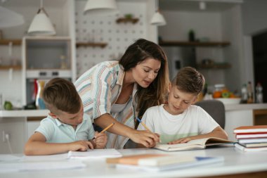 Anne oğullarıyla ödev yapıyor.