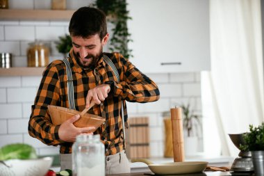 Mutfaktaki yakışıklı adamın portresi. Genç adam lezzetli yemekler hazırlıyor..