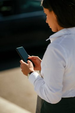 Ofis binasının yanında yürürken elinde cep telefonuyla işe giden güzel bir kadın..