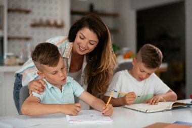 Anne oğullarıyla ödev yapıyor.
