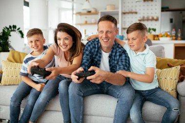 Karı koca oturma odasında joysticklerle oyun oynuyorlar. Sevgili çift evde çocuklarla video oyunu oynuyor..