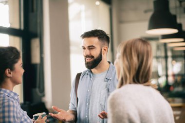 Modern açık uzay ofisinde sıradan iş adamlarından oluşan bir grup. İş kadınları ve işadamları yeni proje hakkında konuşuyor.