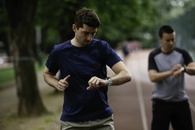 Gençler yarış pistinde antrenman yapıyor. İki genç arkadaş atletizm pistinde koşuyor.