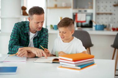 Baba, oğluna ev ödevinde yardım ediyor. Küçük çocuk evde öğreniyor..