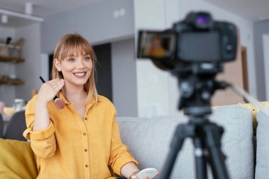 Kadın video kaydedicisi, kanalı için makyaj dersi kaydediyor. Sosyal medyada paylaşmak için makyaj dersi alan genç ve güzel bir kadın..