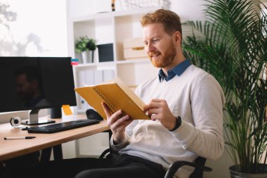 Genç yakışıklı işadamı ofiste notlar okuyor.