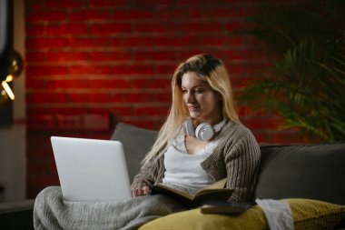 Güzel bir genç kadın evinde dizüstü bilgisayar çalışıyor ve çalışıyor..