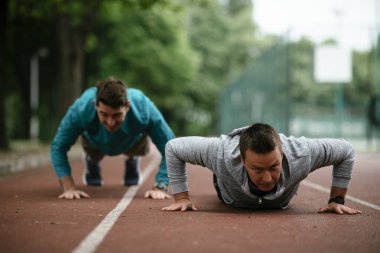 Yarış pistinde egzersiz yapan genç adamlar. Dışarıda antrenman yapan iki genç arkadaş..