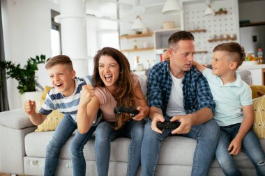 Karı koca oturma odasında joysticklerle oyun oynuyorlar. Sevgili çift evde çocuklarla video oyunu oynuyor..