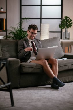 Evde pantolonsuz çalışan bir iş adamı. Genç adam video görüşmesi sırasında bilgisayarı kullanıyor..