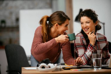 Açık uzay ofisinde konuşan ve gülen mutlu iş kadınları