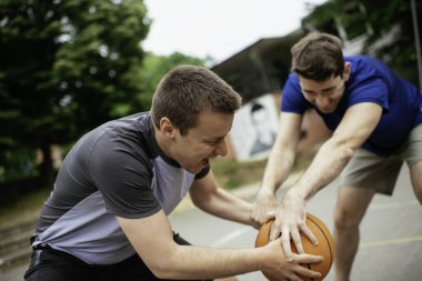 Parkta basketbol oynayan iki genç adam. Arkadaşlar dışarıda dostça bir maç yapıyor.