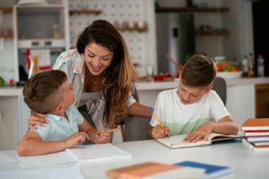 Anne oğullarıyla ödev yapıyor.