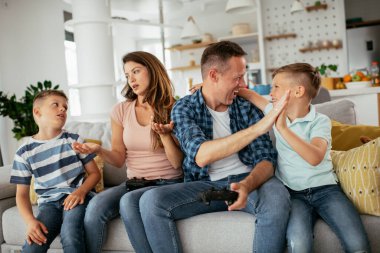 Karı koca oturma odasında joysticklerle oyun oynuyorlar. Sevgili çift evde çocuklarla video oyunu oynuyor..