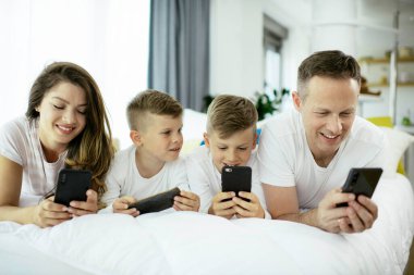 Cep telefonu kullanan bir aile. Aileler ve çocuklar evde akıllı telefon kullanıyorlar..
