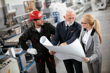 Mimarlar ve işçiler yeni projeyi planlarıyla tartışıyorlar. Fabrikada çalışan meslektaşlar..