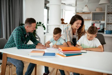 Ebeveynler çocuklara ev ödevlerinde yardım ediyorlar. Küçük çocuklar evde öğreniyor..