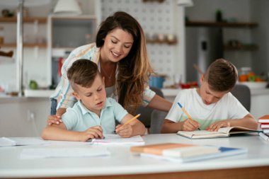 Anne oğullarıyla ödev yapıyor.