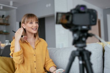 Kadın video kaydedicisi, kanalı için makyaj dersi kaydediyor. Sosyal medyada paylaşmak için makyaj dersi alan genç ve güzel bir kadın..