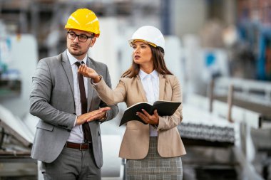 Erkek ve kadın iş tartışıyorlar. Fabrikada çalışan meslektaşlar.