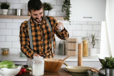 Mutfaktaki yakışıklı adamın portresi. Genç adam lezzetli yemekler hazırlıyor..