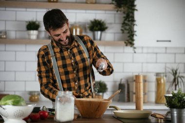 Mutfaktaki yakışıklı adamın portresi. Genç adam lezzetli yemekler hazırlıyor..