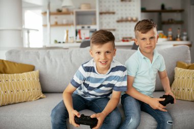 brothers playing video games. Young brothers having fun while playing video games in living room.
