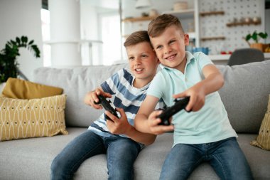 Video oyunu oynayan mutlu kardeşler. Küçük kardeşler oturma odasında video oyunu oynarken eğleniyorlar..