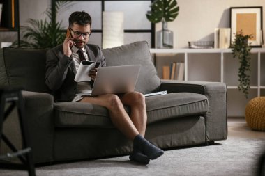 Evde pantolonsuz çalışan bir iş adamı. Genç adam video görüşmesi sırasında bilgisayarı kullanıyor..