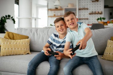 brothers playing video games. Young brothers having fun while playing video games in living room.